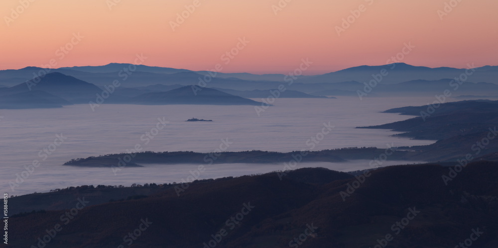 Fog filling a valley at sunset, with hills and mountains emerging like islands