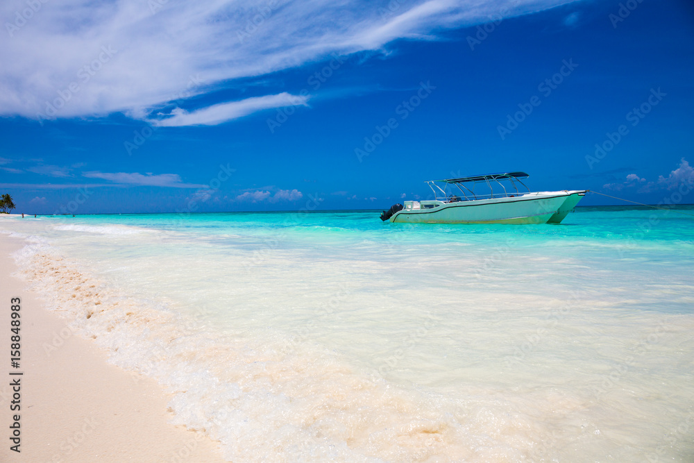 boat on tropical beach with blue water background