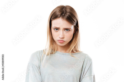 Sad young woman standing isolated over white background