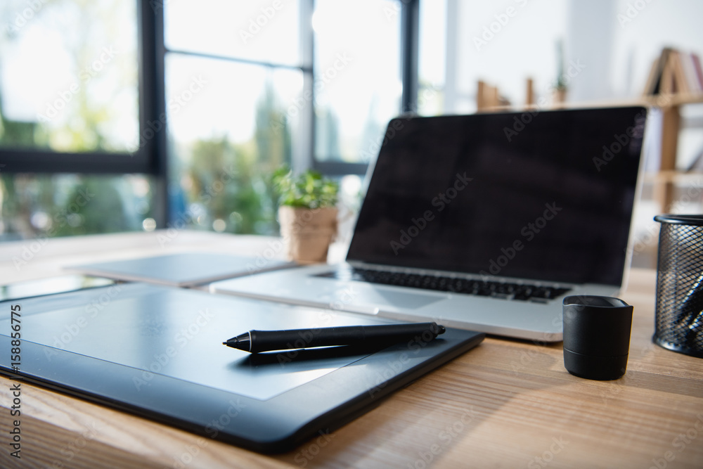 laptop with blank screen and graphics tablet on wooden tabletop at office laptop with blank screen and graphics tablet on wooden tabletop at office