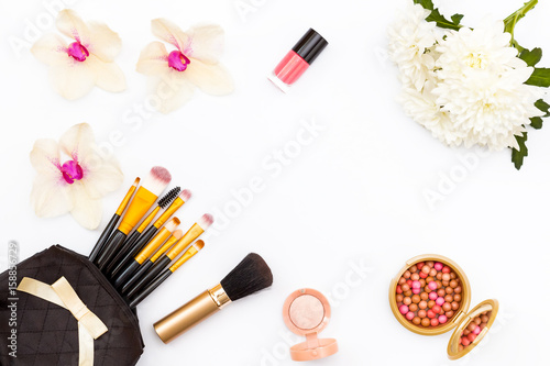 Makeup brushes in black bag, flowers, Orchid and chrysanthemum, nail Polish and other cosmetics on a white background.