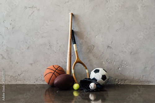 Valokuvatapetti Close-up view of various balls and sports equipment near grey wall