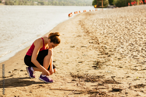 Φωτογραφία Woman lacing sport shoes and getting ready for running and exercising at beach o