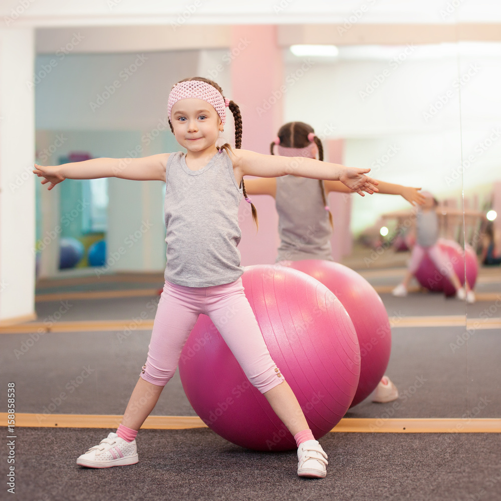 Φωτογραφία Girl child doing fitness exercises on the fitness ball in health club, stretching in exercise