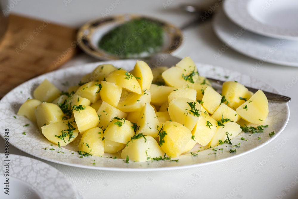 Steamed potato with dill and parsley on white plate Steamed potato with dill and parsley on white plate