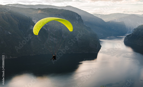Paraglider silhouette flying over Aurlandfjord, Norway