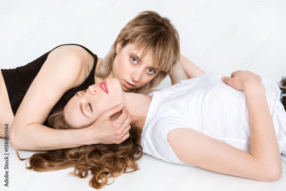 Sensual young lesbian couple lying together isolated on white Sensual young lesbian couple lying together isolated on white