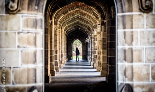 A stone arch hallway at a university with unidentified female in the distance
