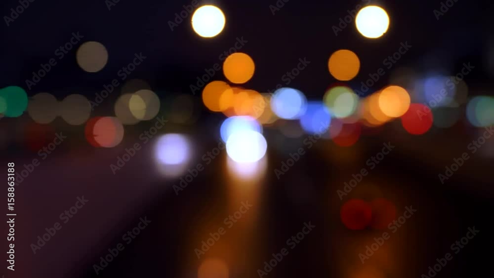 The headlights of moving cars are not focused. Large colored light spots move toward the camera. Dark background. The headlights of moving cars are not focused. Large colored light spots move toward the camera. Dark background.