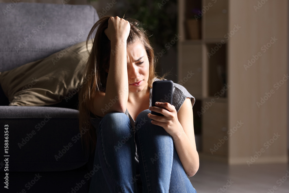 Sad teen checking phone at home Sad teen checking phone at home