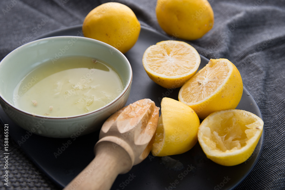 Juicing fresh yellow lemons on dark moody background Juicing fresh yellow lemons on dark moody background