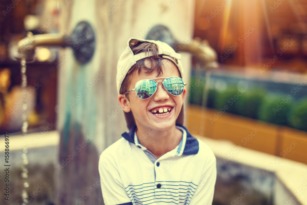 Happy little caucasian boy in cap laughing outdoor at summer, vintage style
