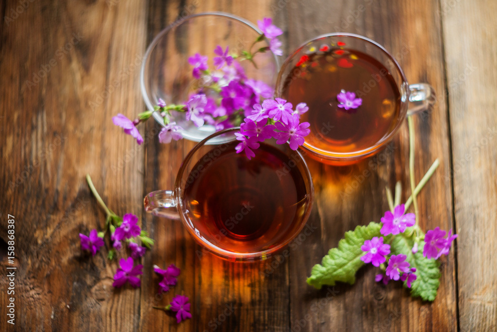 Lime brewed tea in a cup on a wooden table. on a table scattered linden blossoms and leaves Lime brewed tea in a cup on a wooden table. on a table scattered linden blossoms and leaves