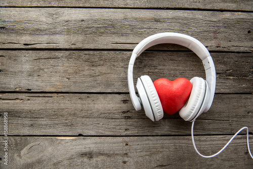 White headphones with red heart sign in the middle on wooden background