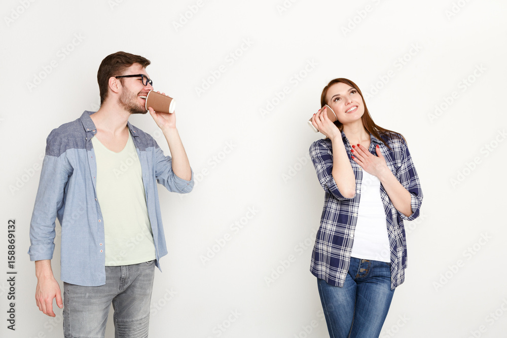 Young casual couple talking through tin can phone Young casual couple talking through tin can phone