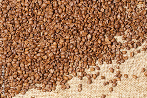 Roasted spilled coffee beans on sackcloth background © anatmari