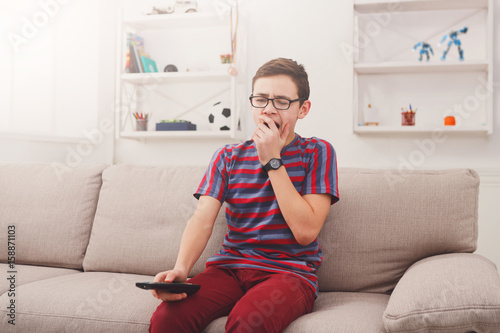 Bored teenage boy watching tv at home