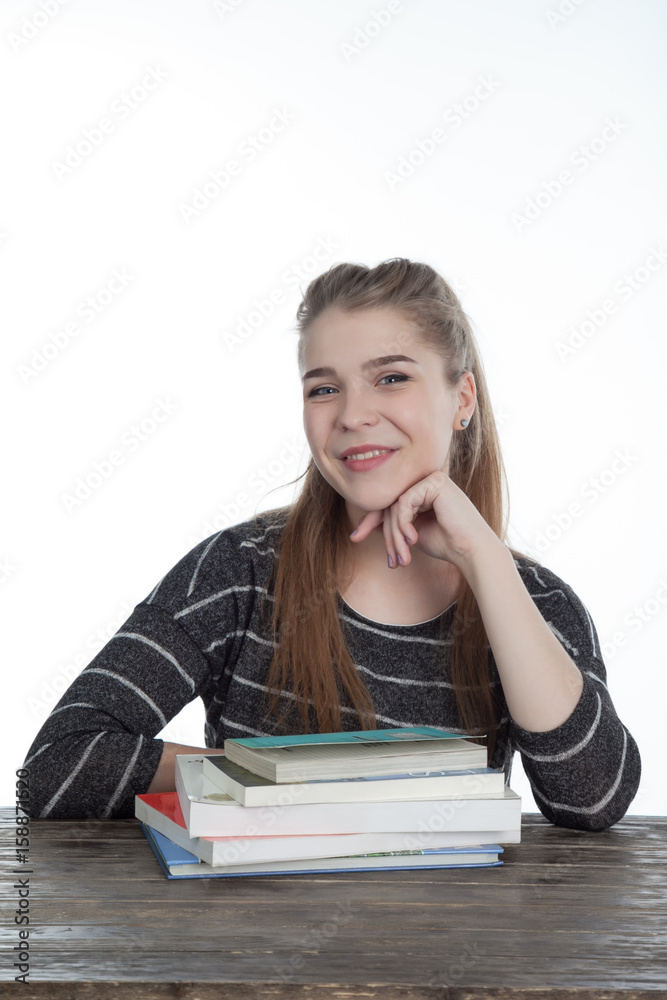 Student women sitting on wood table with her hands and shoulder on the books. Smiling Girl with books, on wooden table and white background. Close-up on white background. Student women sitting on wood table with her hands and shoulder on the books. Smiling Girl with books, on wooden table and white background. Close-up on white background.