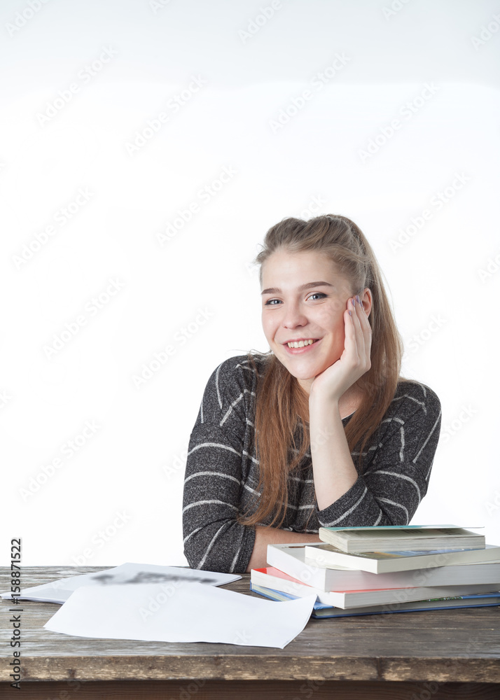 Student women sitting on wood table with her hands and shoulder on the books. Smiling Girl with books, on wooden table and white background. Close-up on white background. Student women sitting on wood table with her hands and shoulder on the books. Smiling Girl with books, on wooden table and white background. Close-up on white background.