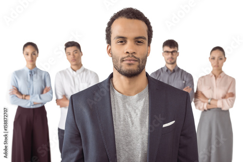 portrait of afro-american businessman standing in front of his colleagues isolated on white