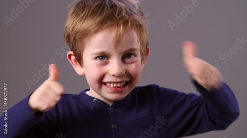 joyous preschool boy showing his satisfaction with double thumbs up