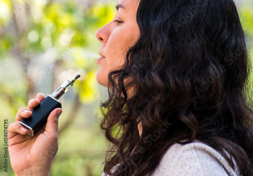 Mature woman outdoors, smoking electronic cigarette photo