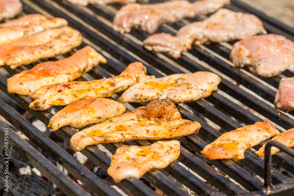 Chicken breasts and pork meat frying on the barbecue grill