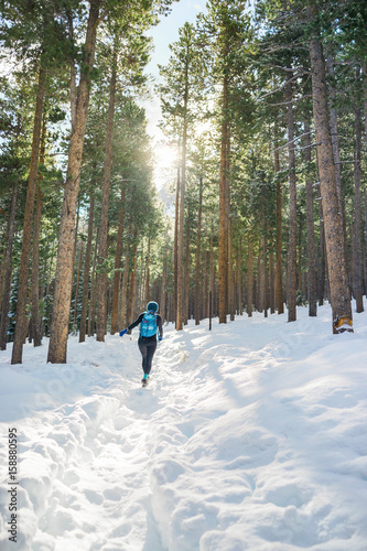 A female hiker hikes in the forest with snow in winter.