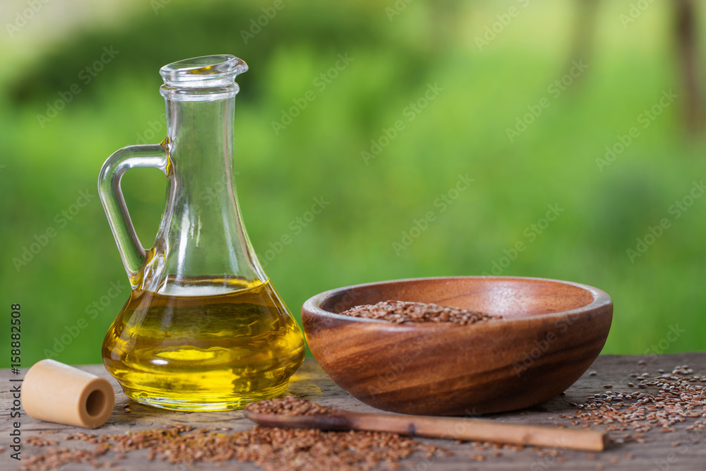 flax seeds and linseed oil in a glass jug on a wooden table flax seeds and linseed oil in a glass jug on a wooden table