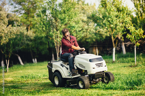 Portrait of industrial worker using lawn mower for cutting grass