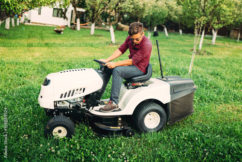Landscaping details - worker mowing lawn with professional tools in garden