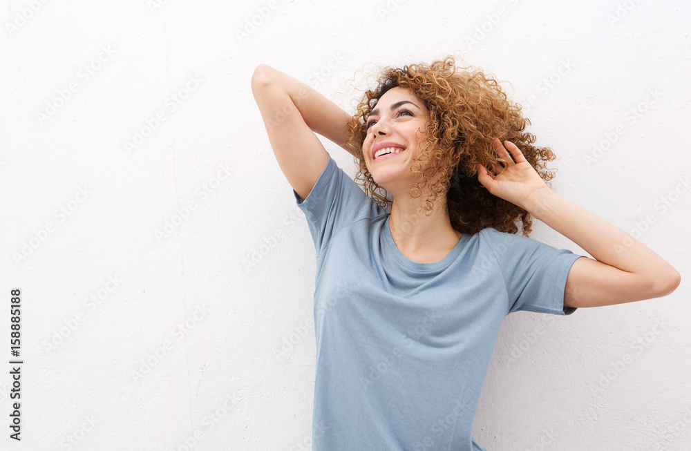 happy woman laughing with hand in hair against white wall happy woman laughing with hand in hair against white wall