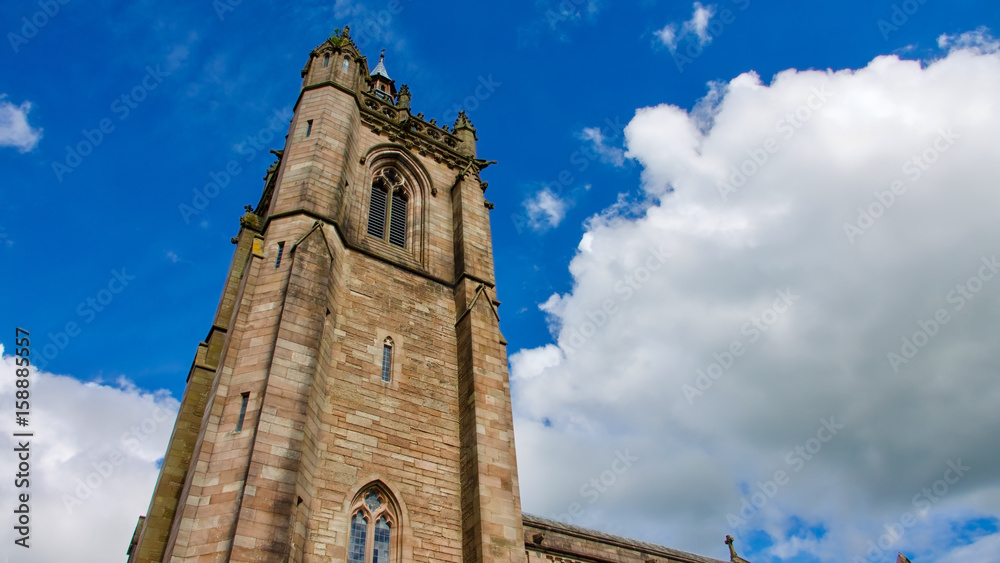 Fototapeta premium Square church tower against a blue sky with white clouds