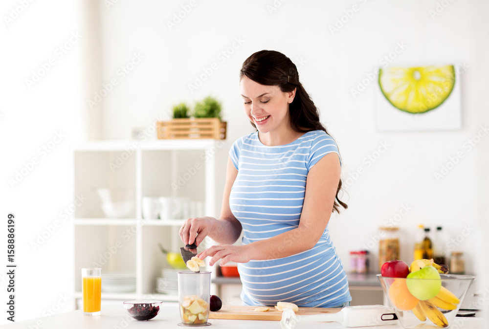 pregnant woman putting fruits to blender at home