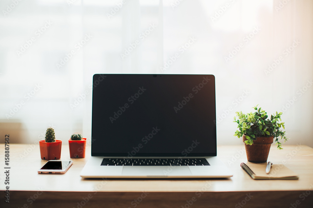 Close-up of comfortable working place in office with wooden table and laptop laying on it Close-up of comfortable working place in office with wooden table and laptop laying on it