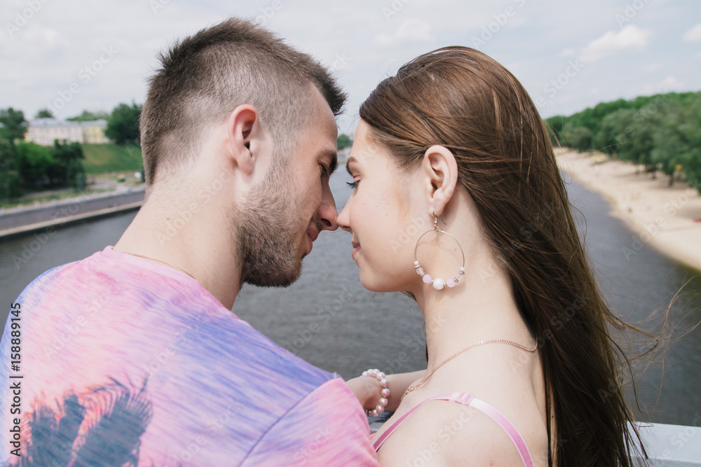 Young couple hugging and smiling each other walking on a bridge Young couple hugging and smiling each other walking on a bridge