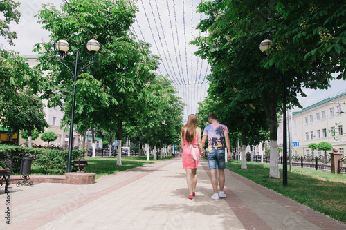 A loving couple is walking along the avenue on a sunny day