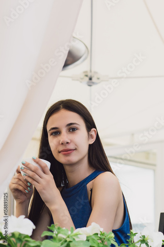 A very beautiful business woman sits in a cafe and holds a cup of coffee in her hands