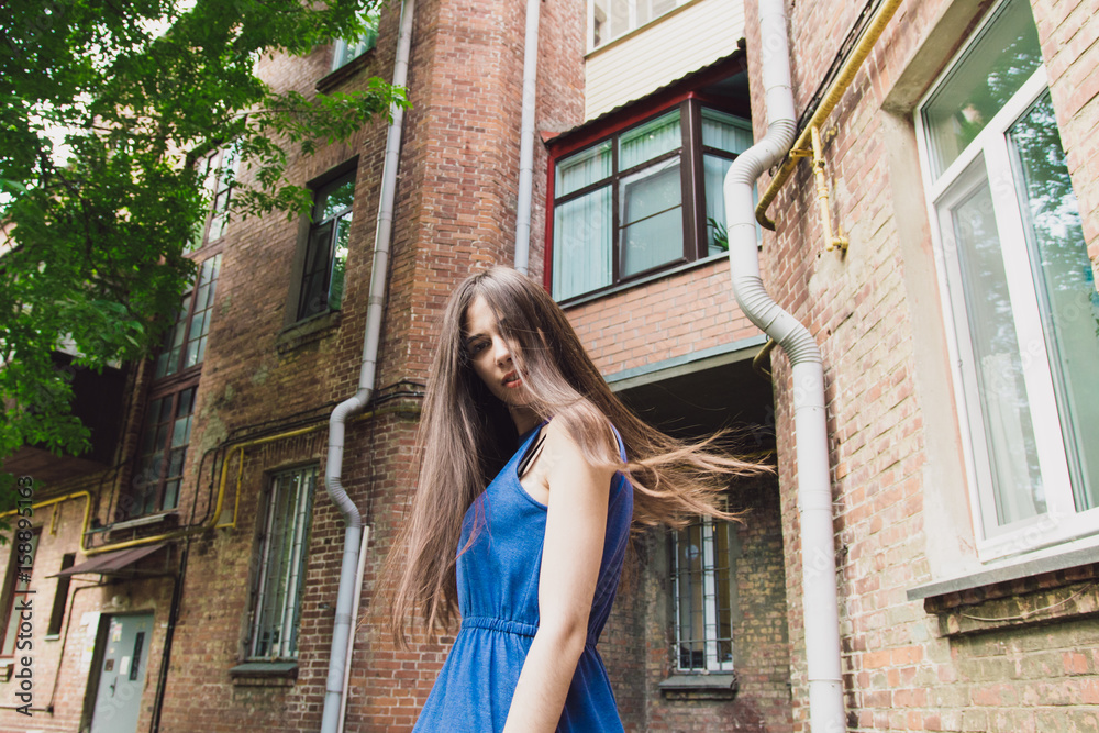 A very beautiful and cheerful girl stands on the street near a brick wall A very beautiful and cheerful girl stands on the street near a brick wall