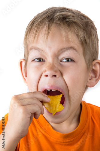 The boy is hungrily eating chips
 photo