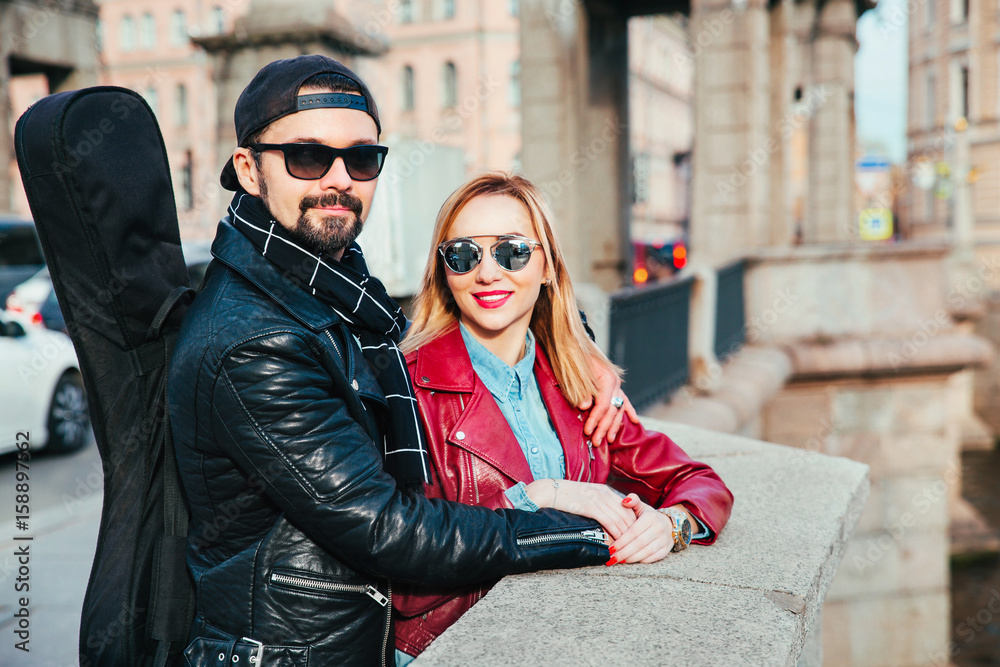 Beautiful couple in sunglasses on the bridge in city . Rock style .