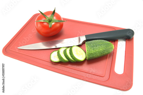 Огурец помидор и нож на разделочной доске 