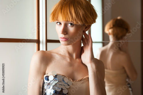 Elegant beautiful blonde woman posing in studio, wearing fashionable dress