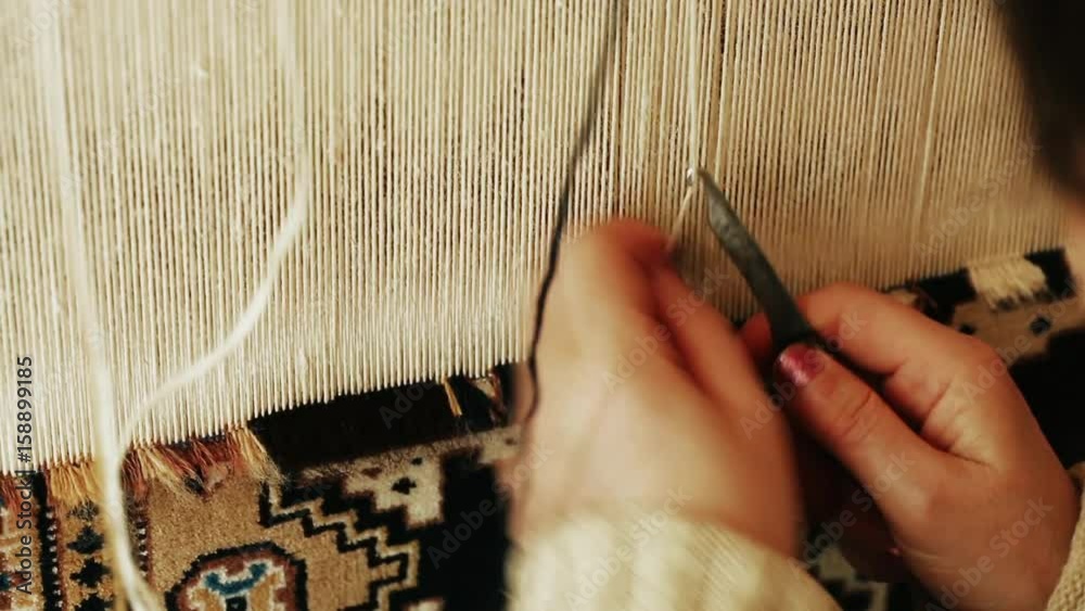 Carpet weaving.  Turkish woman weaving a carpet with peace of genuine camel wool with a manual waving machine. Needlework. Carpet-makers work close-up video.