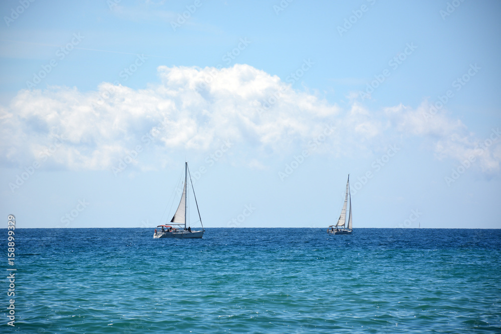 White sailboat in the Mediterranean sea, beautiful cumulus clouds
