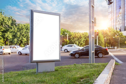 Blank white mock up of vertical light box in a bus stop in beautiful weather
