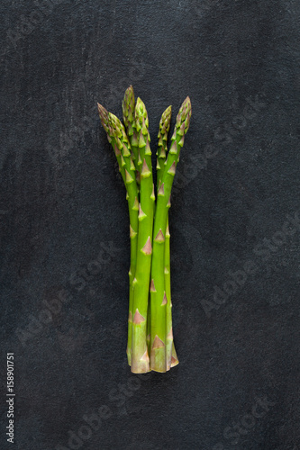 Bunch of green fresh asparagus isolated on dark gray slate