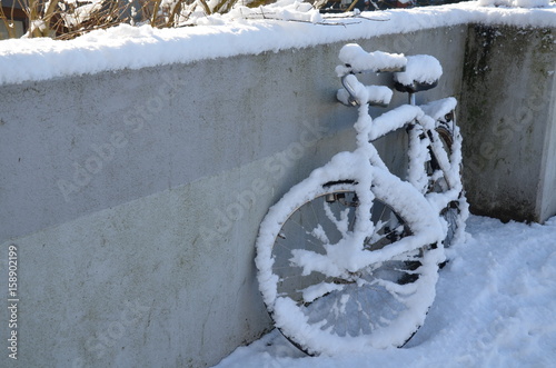 Isolated vintage bicycle covered by snow. Bicycle is parked on concrete wall. Romantic winter photo from Amsterdam.