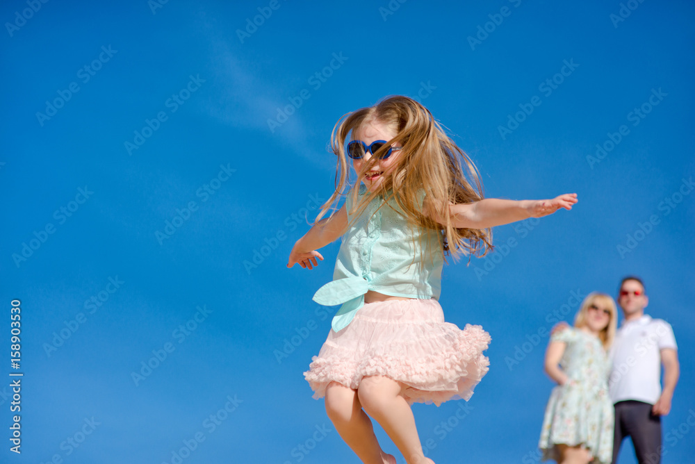 Beautiful happy family walking, running, jumping, having fun along the sand on the beach against the background blue sky in summer vacation Beautiful happy family walking, running, jumping, having fun along the sand on the beach against the background blue sky in summer vacation