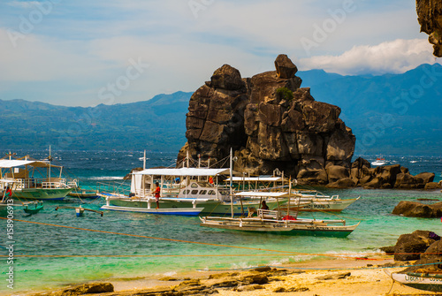 Apo island, Philippines, view on island beach line: sea, rocks and boats. photo